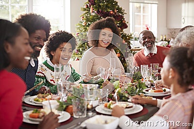 Happy multi generation mixed race family sitting at their Christmas dinner table eating and talking, selective focus Stock Photo