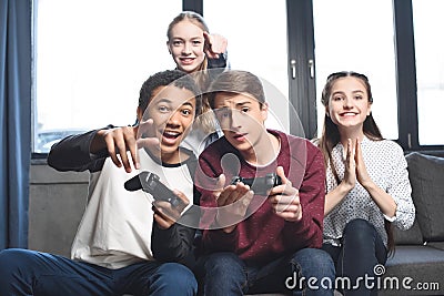 Happy multicultural teenagers playing video games with joysticks at home Stock Photo