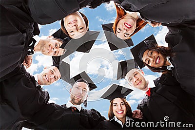 Happy multiethnic graduates forming huddle against sky Stock Photo