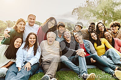 Happy multigenerational people having fun sitting on grass in a public park Stock Photo