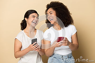 Happy multiracial diverse millennial women holding smartphones, laughing. Stock Photo