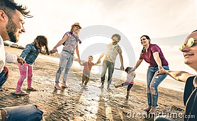 Happy multiracial families round dancing at the beach at sunset Stock Photo