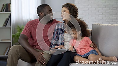 Happy multiracial family planning trip for holidays, booking online on tablet Stock Photo