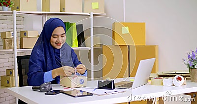 Beautiful muslim female merchandiser preparing parcel at the office Stock Photo