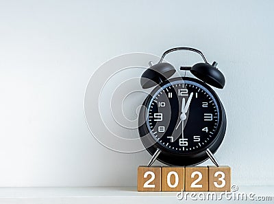 2023 Happy New year background. 2023 calendar number on wooden cube blocks with black alarm clock. Stock Photo