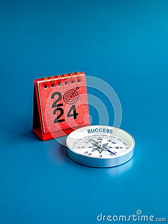2024 numbers year with target dart icon on red desk calendar cover stand and compass on blue background. Stock Photo
