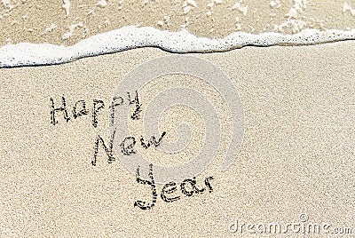 Happy New Year caption on sea beach sand with wave Stock Photo