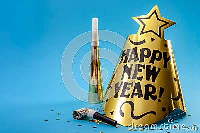 Happy new year concept with a festive hat, noisemakers, confetti, party blower and paper trumpet isolated on blue background with Stock Photo