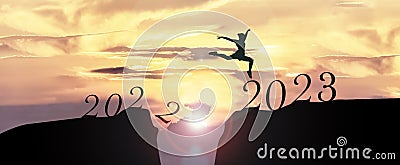 2023 Happy New Year concept, Young woman Jumping across the gap of the mountain from Old year 2022 to 2023 New Year Stock Photo