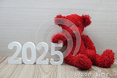 Happy New Year 2025 festive background with teddy bear decoration on wooden background Stock Photo