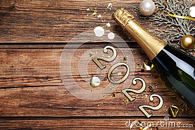 Happy New Year 2022! Flat lay composition with bottle of sparkling wine on wooden table, space for text Stock Photo
