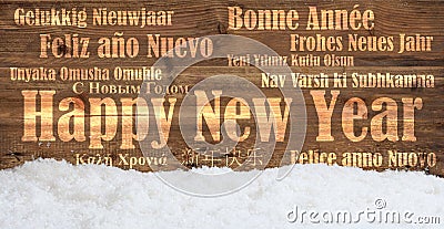 Happy new year in many languages on snowy wooden background Stock Photo