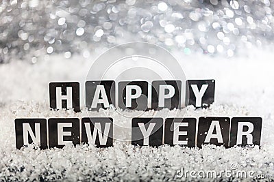 Happy new year text on snow, abstract bokeh lights background Stock Photo