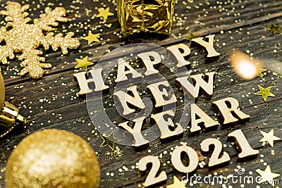 Happy new year 2021 text on wooden background surrounded golden christmas toys and fur tree branch. Festive greeting catd for Stock Photo