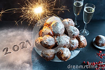 Happy New Year with the year 2021 written icing sugar next to a bowl of oliebollen (Dutch dough fritters) Stock Photo