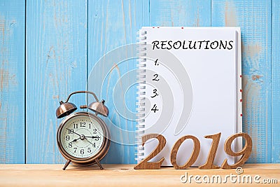 2019 Happy New years with Resolution text on notebook, retro alarm clock and wooden number on table and copy space Stock Photo