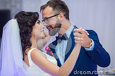 Happy newlywed couple smiling at their first dance at wedding re Stock Photo