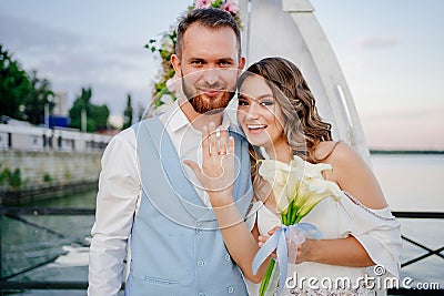 happy newlyweds exchange rings. beautiful wedding ceremony by water on dock. Stock Photo