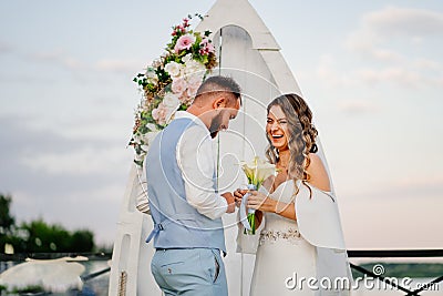 happy newlyweds exchange rings. beautiful wedding ceremony by water on dock. Stock Photo