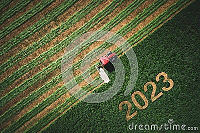 2023 Happy New year concept for agriculture, business, goals, success and new start banner. Industrial tractor on a green field. Stock Photo