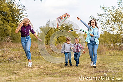 Happy non traditional family of two young mother and their kids launch a kite on nature at sunset Stock Photo