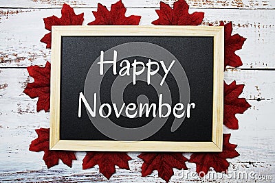 Happy November text on blackboard decorated with red maple leaves on wooden background Stock Photo