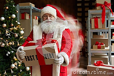Happy Santa in blur motion holding present, fast xmas delivery, Christmas rush. Stock Photo