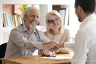 Happy old couple clients make financial deal handshake meeting lawyer Stock Photo