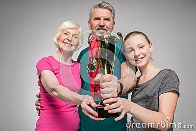 Happy old couple and girl holding sport trophy and medals Stock Photo