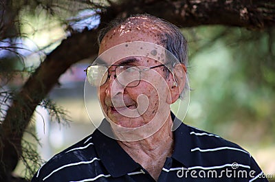 Happy old Argentine grandfather enjoying life waving hi, with big smile, big glasses and confident abuelo Stock Photo