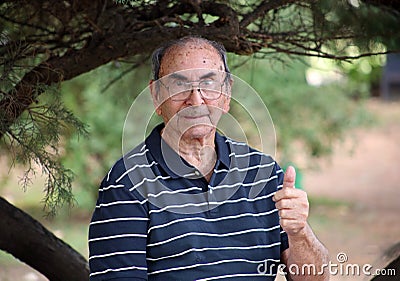Happy old grandfather enjoying life waving hi, with big smile, big glasses and confident abuelo Stock Photo