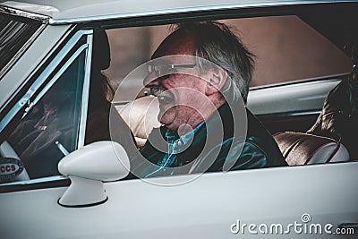 Happy old male laughing while driving an old car during the Reggae festival Editorial Stock Photo