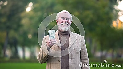 Happy old man holding dollar bills in hand, retirement savings, pension fund Stock Photo