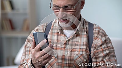 Happy old man holding phone, learning modern technologies, easy app for elderly Stock Photo