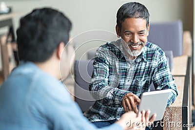 Happy old short beard asian man sitting, smiling and listen to partner that showing presentation on smart digital tablet. Stock Photo