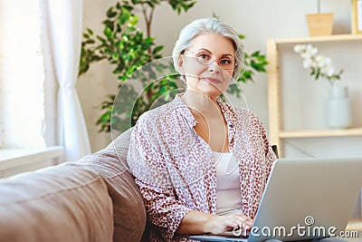 Happy old woman senior working at computer laptop at home Stock Photo