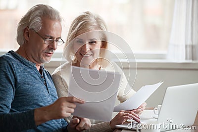 Happy older aged couple holding reading good news in document Stock Photo