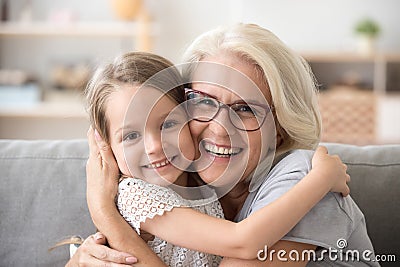 Happy older grandmother hugging little grandchild girl looking a Stock Photo
