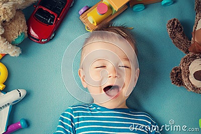 Happy one year old boy lying with many plush toys Stock Photo