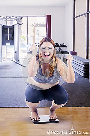 Overweight woman squat down on the weight scales Stock Photo
