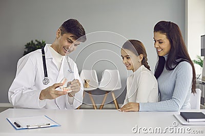 Pediatric dentist or oral hygienist teaching little girl to brush teeth properly Stock Photo