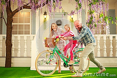 Happy parents with a child, daughter, learn to ride a bike, family lifestyle summer vacations at home Stock Photo