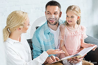 happy parents with cute little daughter reading book together Stock Photo