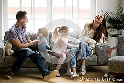 Happy parents and kids having fun tickling sitting on sofa Stock Photo