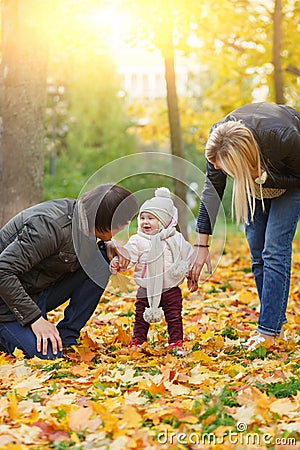 Happy parents look at their daughter in autumn park Stock Photo