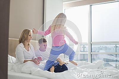 Happy parents looking at playful children in bedroom Stock Photo