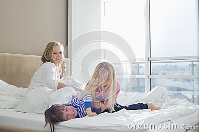 Happy parents looking at playful children in bedroom Stock Photo