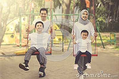 Happy parents pushing their children on a swing Stock Photo