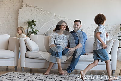 Happy parents watching two hyperactive energetic little sibling kids Stock Photo