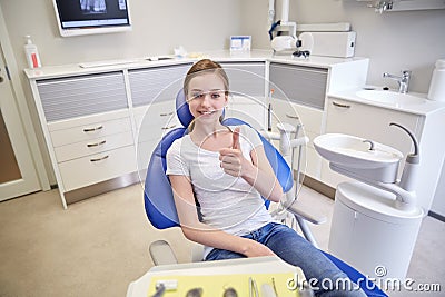 Happy patient girl showing thumbs up at clinic Stock Photo